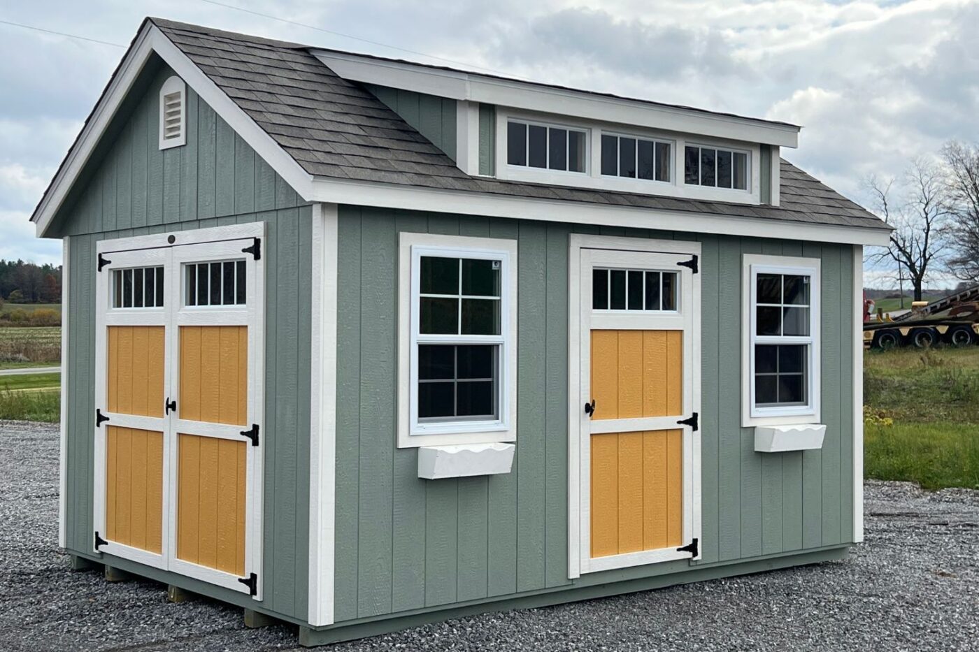 One of our chalet sheds near Cheektowaga NY - Gray green wood with white and mustard colored white trimmed doors - white trimmed windows and gray roof